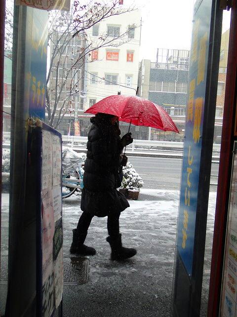 金券ショップ 赤い傘の人【筆者撮影】